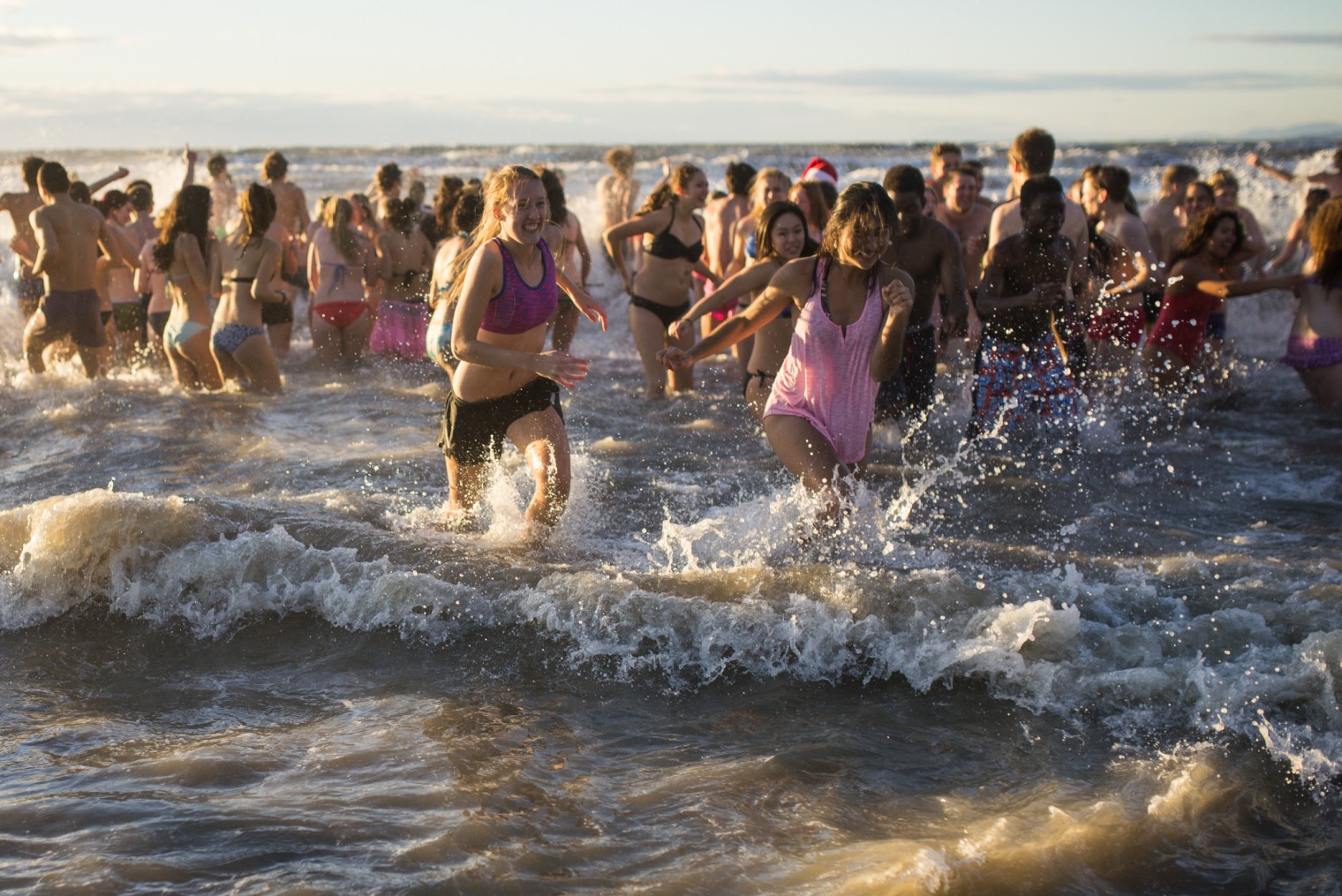 Students run out of the cold ocean water during the Polar Bear Swim at Wreck Beach 