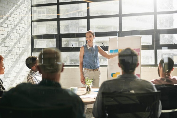 Image of woman presenting in a meeting room full of people