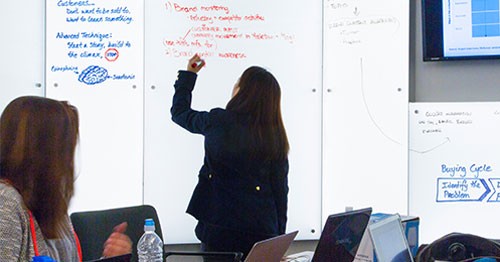 Student or instructor writing on a whiteboard in front of the class