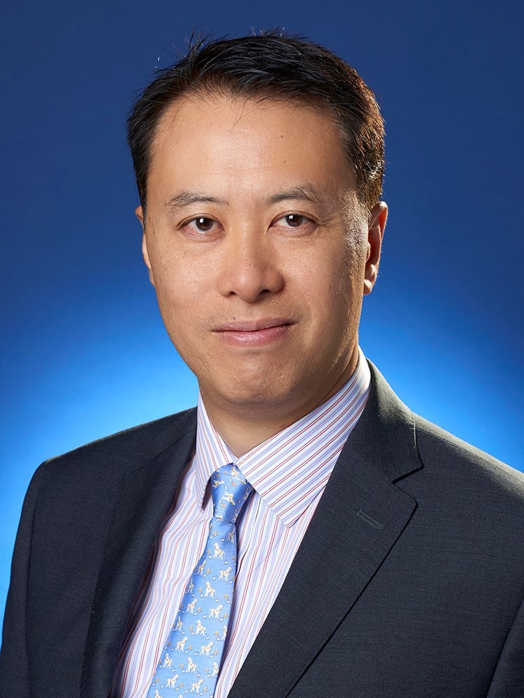 headshot in blue tie and blue background